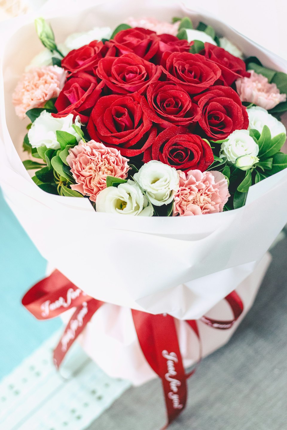 Un mazzo di rose e garofani avvolto in carta bianca.